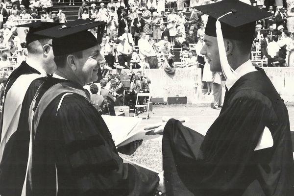 a student accepts his diploma in a black and white photo